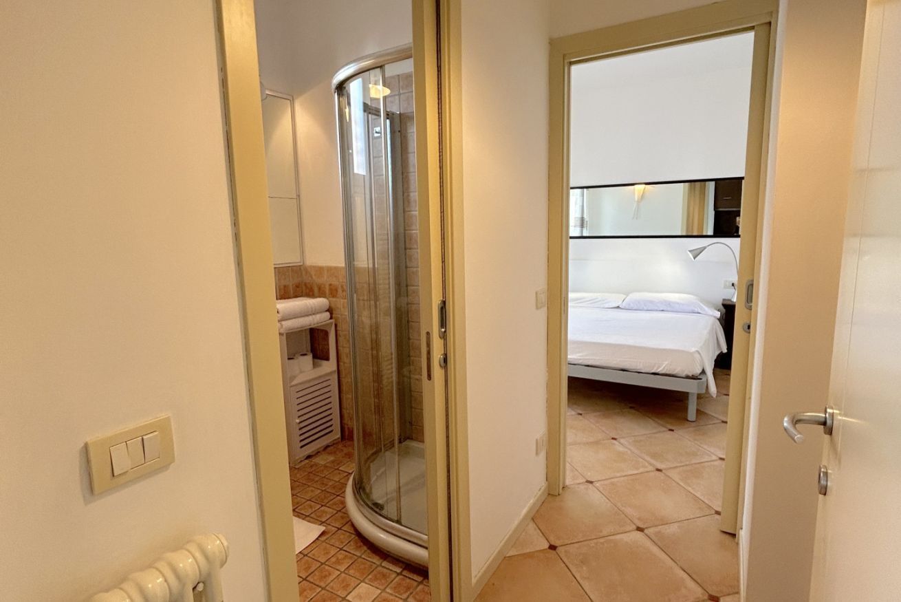 Une chambre d’hôtel avec une douche, un lit et une salle de bain équipée d’un porte-serviettes.