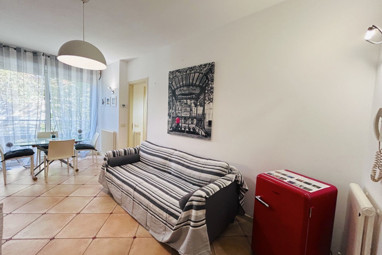 A living room with a striped sofa, a red radiator, and a dining area with a table and chairs.