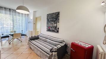 A living room with a striped sofa, a red radiator, and a dining area with a table and chairs.