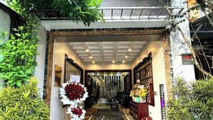 L’entrée d’un hôtel avec un sol en marbre, des plantes d’intérieur et un plafond en verre.