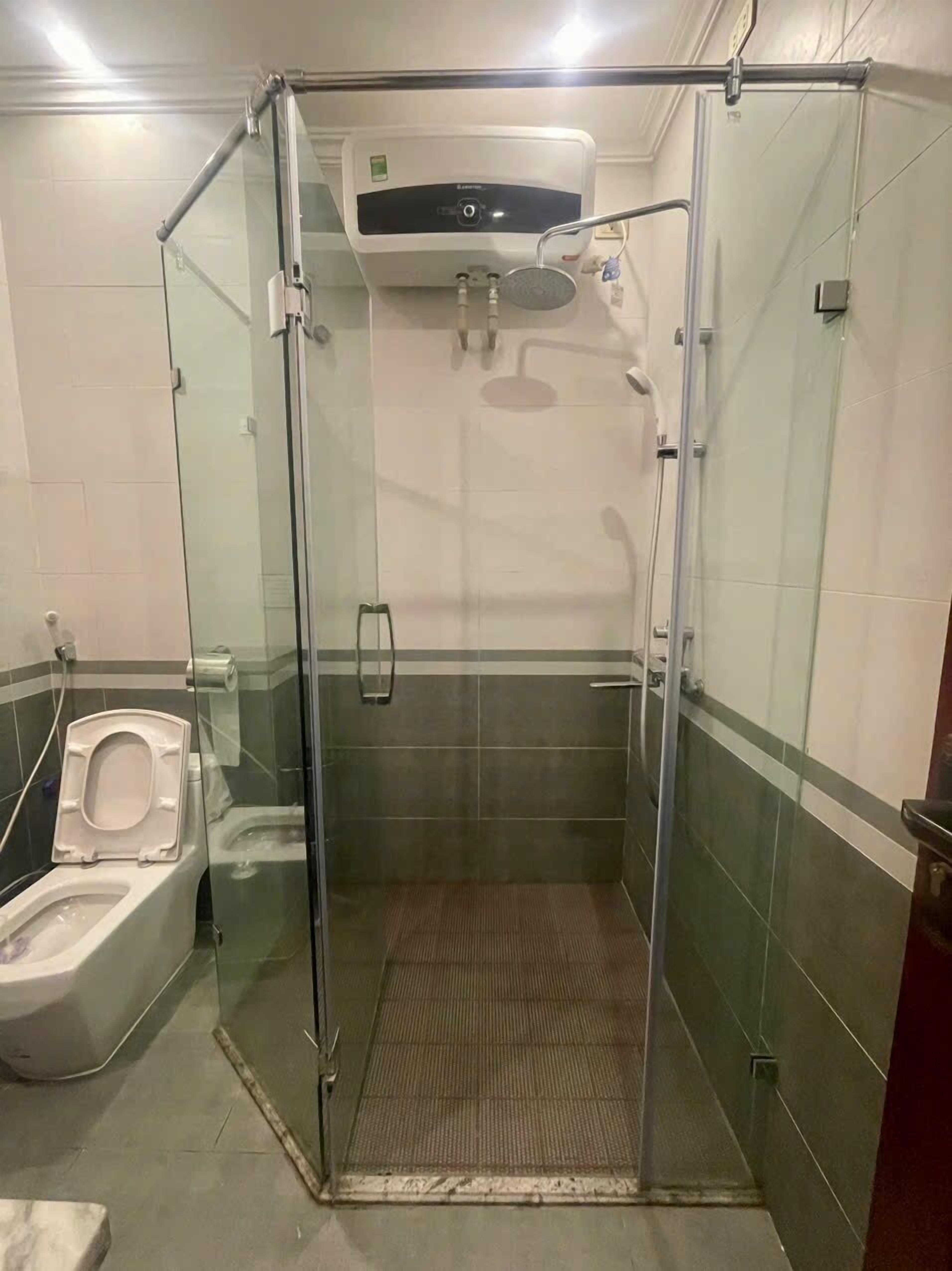 Üvegfalakkal körbeépített zuhanyzó, amelyben WC és kézszárító is található.