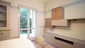 Una camera moderna e minimalista con una grande finestra, una sedia bianca e armadi a muro in legno.