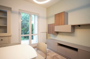 Ein modernes, minimalistisches Zimmer mit großem Fenster, einem weißen Sessel und integrierten Holzausbau.