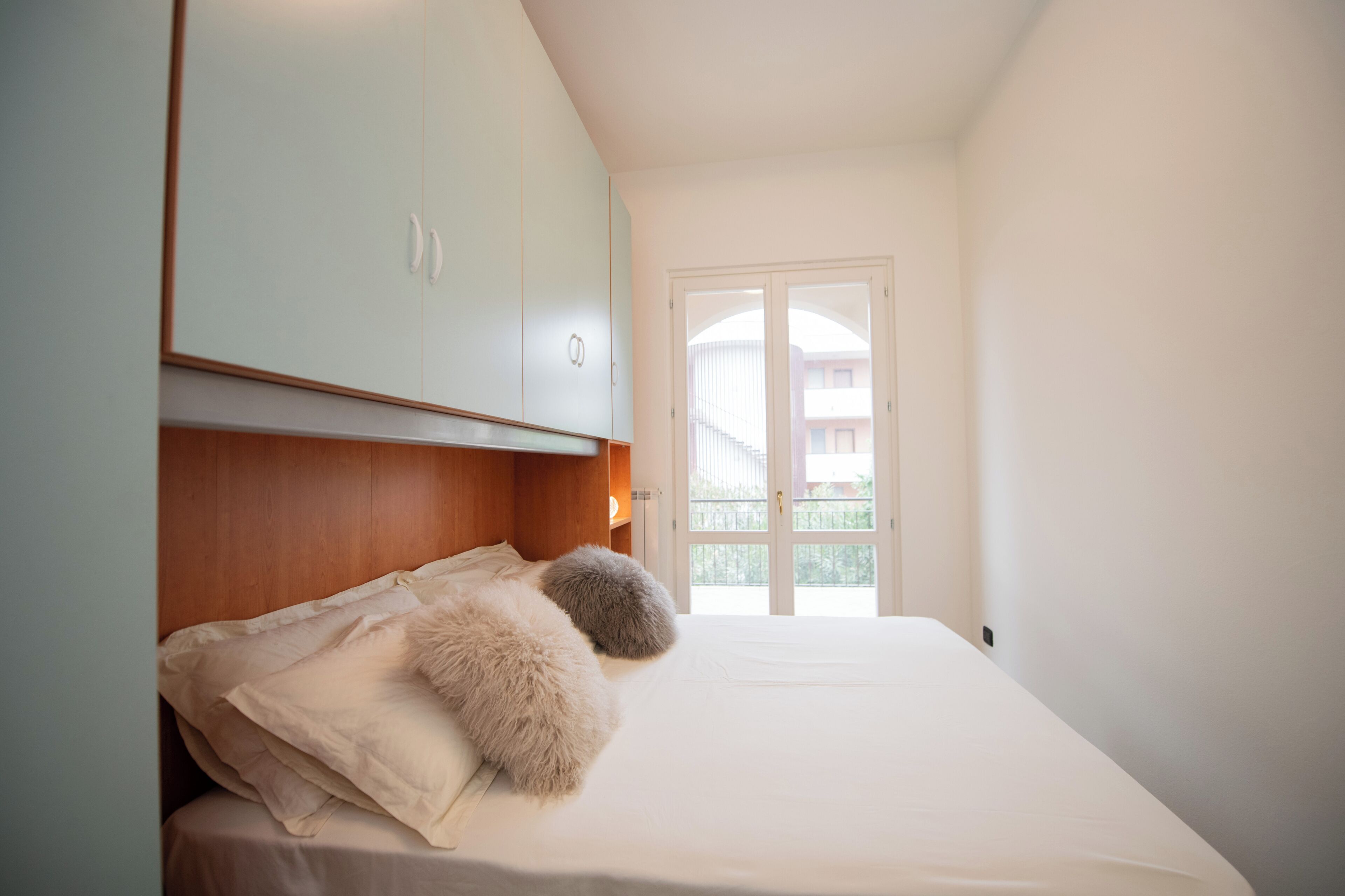 Ein Schlafzimmer mit Bett, Kleiderschrank und Blick auf einen Balkon.