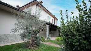 Un edificio con facciata in pietra, un balcone e un giardino con diverse piante.