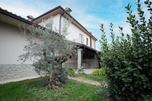 Ein Gebäude mit einer Stein-Fassade, einem Balkon und einem Garten mit verschiedenen Pflanzen.