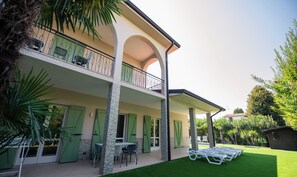 A two-story building with a covered patio area, outdoor seating, and a well-maintained lawn.
