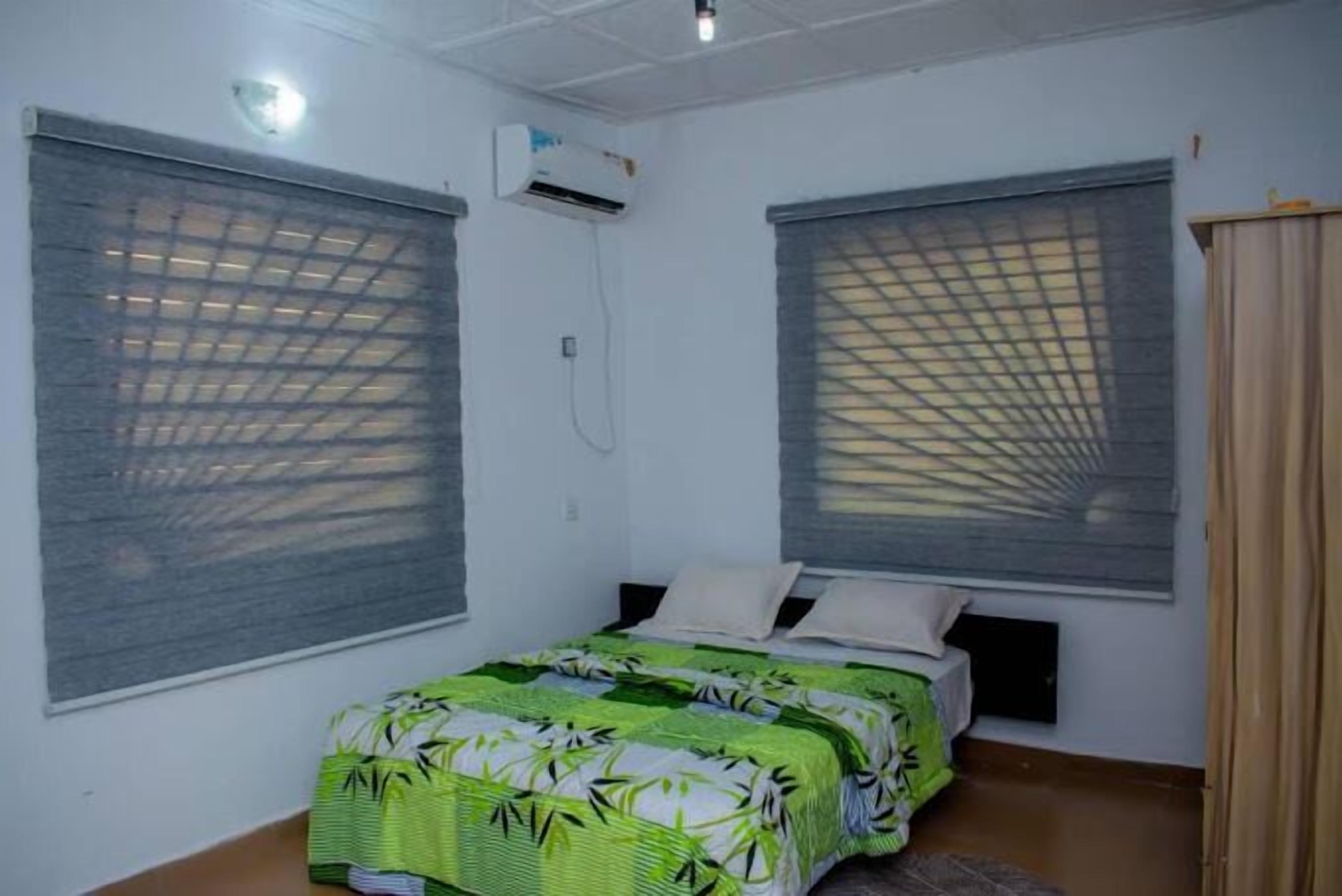 A bedroom with two beds, a ceiling fan, and an air conditioning unit.