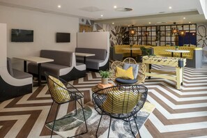 Relax and socialize in this inviting lounge area, featuring a seating space with sofas and chairs, a foosball table, and a TV for entertainment.