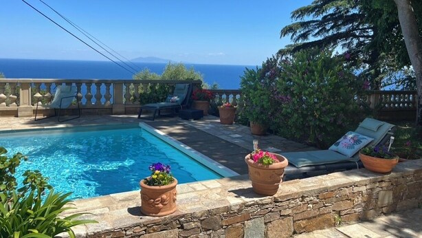 A pool area with a stone wall, lounge chairs, and potted plants. - Ground floor mansion for 6 people with swimming pool and jacuzzi (Bastia)