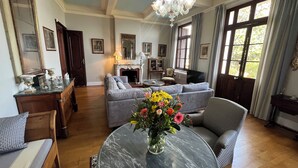 A spacious living room with a marble coffee table, grey sofas, and a chandelier. - Ground floor mansion for 6 people with swimming pool and jacuzzi (Bastia)