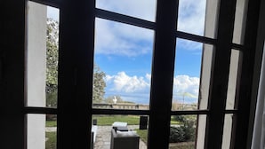 A view through a window with a stone patio, outdoor furniture, and a statue. - Ground floor mansion for 6 people with swimming pool and jacuzzi (Bastia)