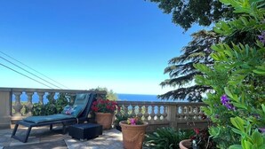 A balcony with a lounge chair, potted plants, and a view of the sea. - Ground floor mansion for 6 people with swimming pool and jacuzzi (Bastia)