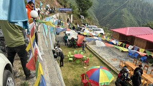 Une zone montagneuse aménagée avec des tables et des chaises pour les repas, un bâtiment à toit rouge et une clôture ornée de drapeaux.