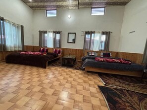 A room with two beds, a small table, and a patterned rug.