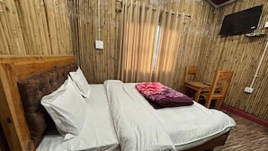 Un lit en bois avec du linge de lit blanc et gris, un oreiller rouge et une tête de lit en bois.