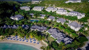 Un complexe hôtelier comprenant plusieurs bâtiments, une plage avec des parasols bleus et une piscine.