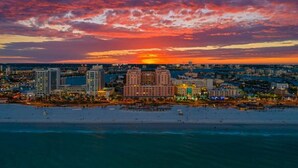 Ein Küsten-Stadtbild bei Sonnenuntergang mit Wolkenkratzern und einem Strand.