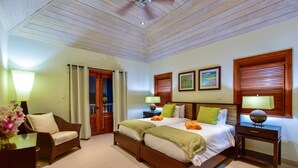 Une chambre d’hôtel avec un lit en bois, deux tables de chevet avec des lampes, une chaise et un bureau.