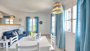 A dining area with a white table, blue curtains, and a blue sofa.