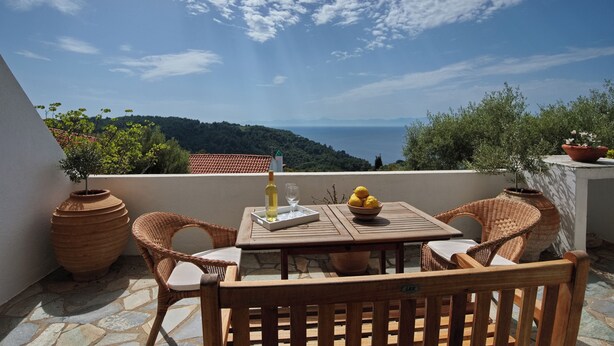 A wooden table with chairs on a balcony overlooking a scenic view.