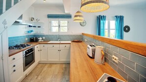 A modern kitchen with white cabinets, a wooden countertop, a gas stove, and a toaster.