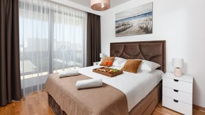 A modern hotel room with a large bed, a bedside table with a lamp, a tray of fruit and juice, and a painting on the wall. - Villa Sunlight Zadar Villas (Zadar)