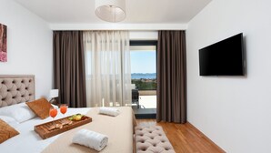 A hotel room with a bed, a breakfast tray, a TV, and a balcony with curtains. - Villa Sunlight Zadar Villas (Zadar)