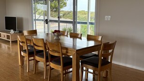 A dining area with a wooden table and chairs, a bowl of fruit, and a television on a stand.