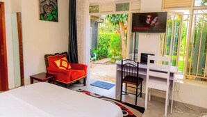 Ein Hotelzimmer mit Bett, Schreibtisch, Stuhl, Fernseher und Blick ins Freie.