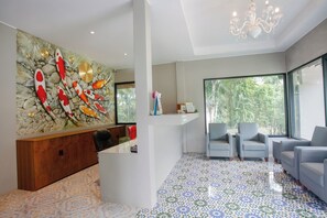 Un interior moderno con un mural de pared de piedra, una recepción y un área de estar con ventanas amplias.