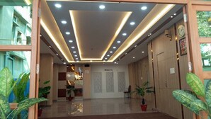 Un vestíbulo de hotel con diseño moderno, que cuenta con una entrada de cristal, un mostrador de recepción de madera y plantas en macetas.