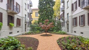 A courtyard with a central tree, surrounded by buildings with balconies and windows.