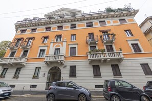 A multi-story building with balconies, a central entrance, and parked cars. - ERCOLE FERRAIO, 12 – Spacious and bright apartment (Milano)