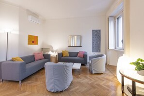 A modern living room with grey sofas, a coffee table, and a small table with a plant.