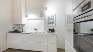 A modern kitchen with white cabinetry, a built-in oven, a sink, and a pendant light.