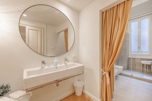 Un baño con un espejo redondo, un lavabo blanco y una cortina de ducha.