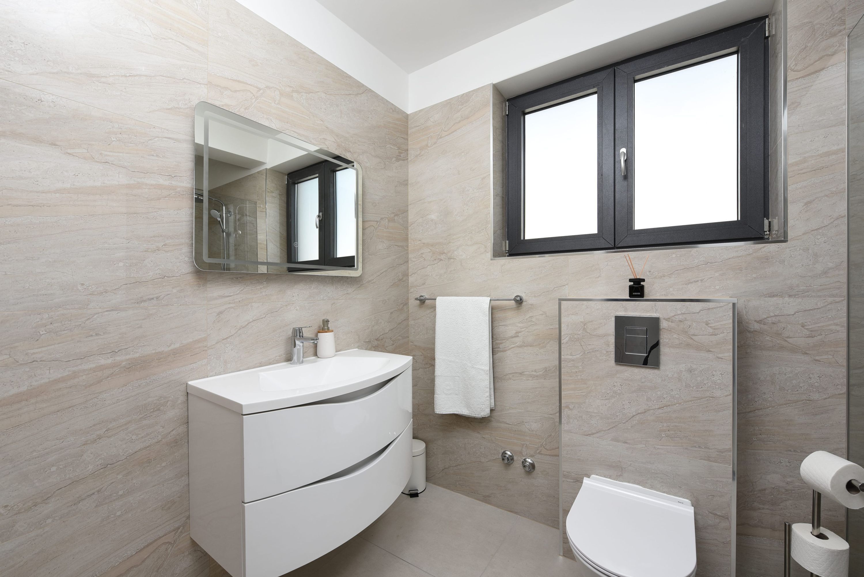 A modern bathroom with a white vanity, a glass shower enclosure, and a toilet.