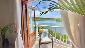 A balcony with a view of a lake, a chair with a cushion, and a potted plant. - Waterfront Nonsuch Bay Villa, 3 en-suite Bedrooms, Pool (FreeTown)