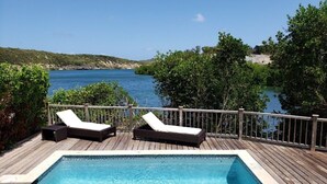 A swimming pool with two sun loungers on a wooden deck overlooking a body of water. - Waterfront Nonsuch Bay Villa, 3 en-suite Bedrooms, Pool (FreeTown)