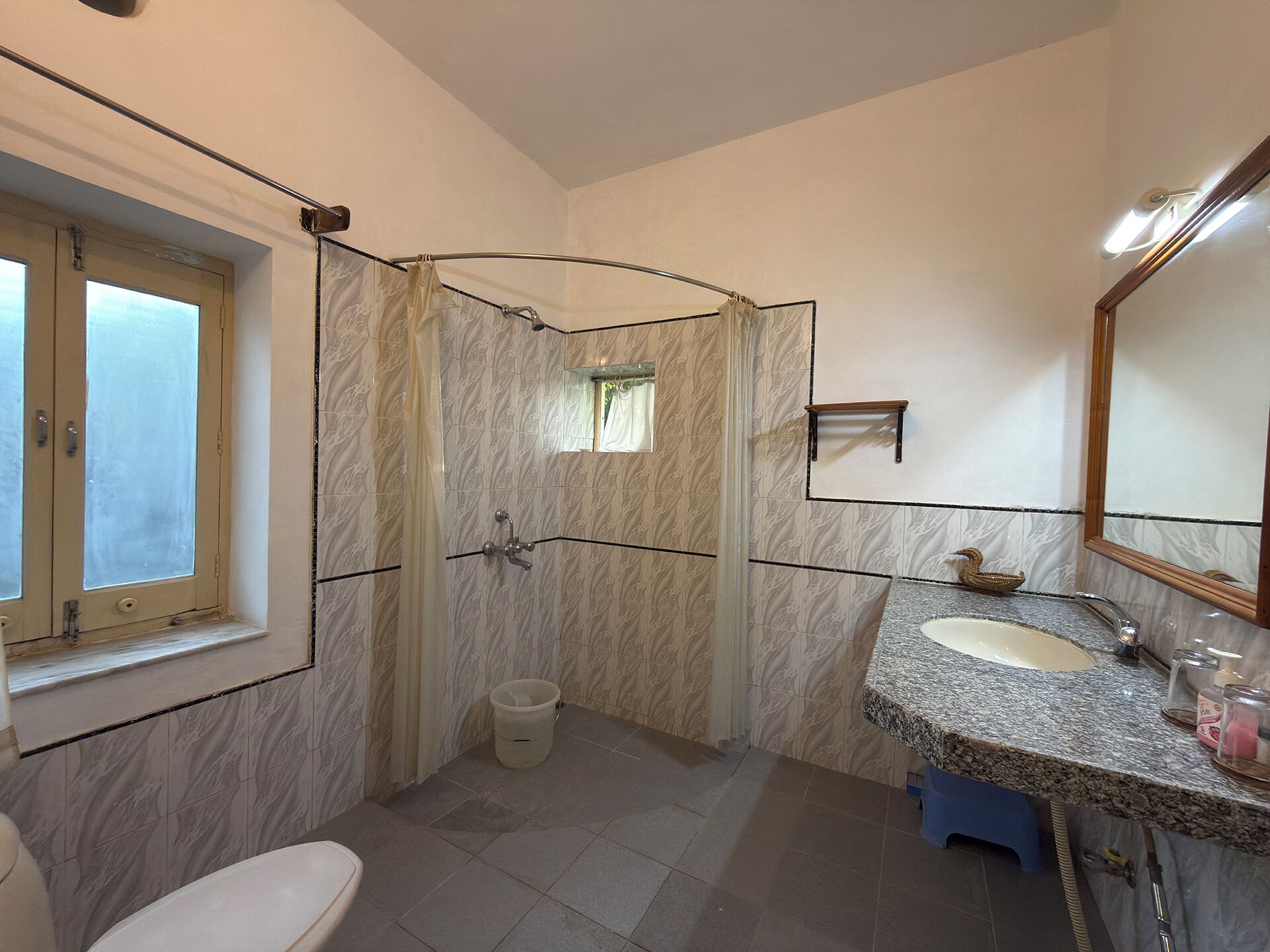 A bathroom with a shower, toilet, sink, and a window.