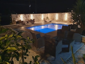 An outdoor swimming pool with stone walls and lounge chairs.