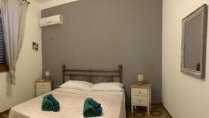 A bedroom with a bed, two nightstands, a mirror, and a window with curtains. - Apartment 1-Villa Augusta del Sol (Fontane Bianche)