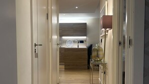 A hallway with wooden flooring, white walls, and a kitchen area in the distance. - Cozy Riverview London Apartment Near the o2 Arena (London)