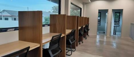 Un espacio de oficina moderno con escritorios de madera largos y sillas de oficina negras, ventanas grandes y suelo de hormigón.