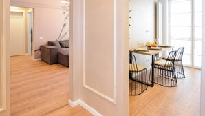 A spacious living area with a wooden floor, a dining table with chairs, and a sofa.