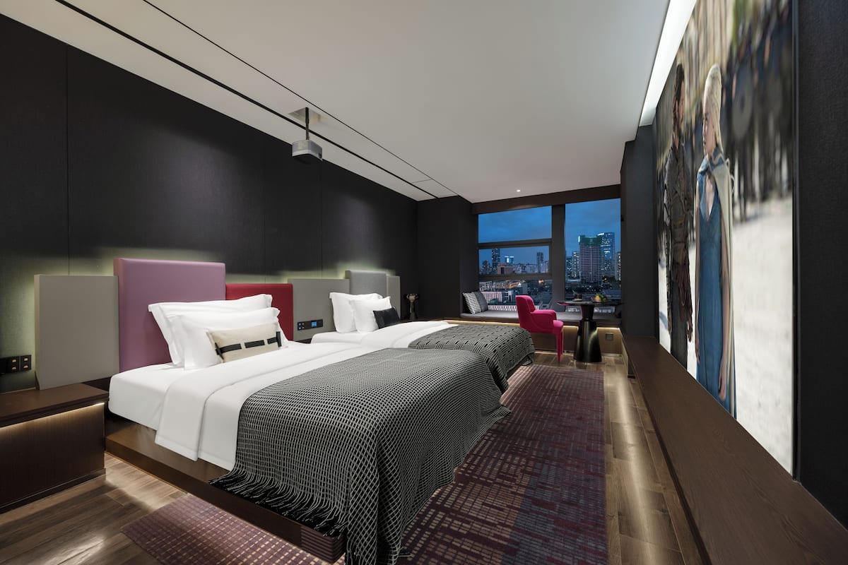 Een moderne hotelkamer met een groot bed, een bureau en uitzicht op de stad.