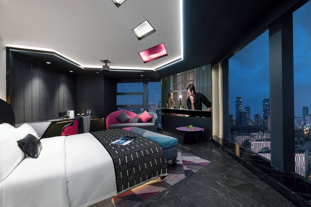 Een moderne hotelkamer met een groot bed, een zithoek en uitzicht over de stad.