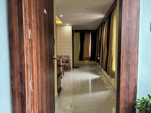 A hallway with wooden doors, a sofa, and curtains.