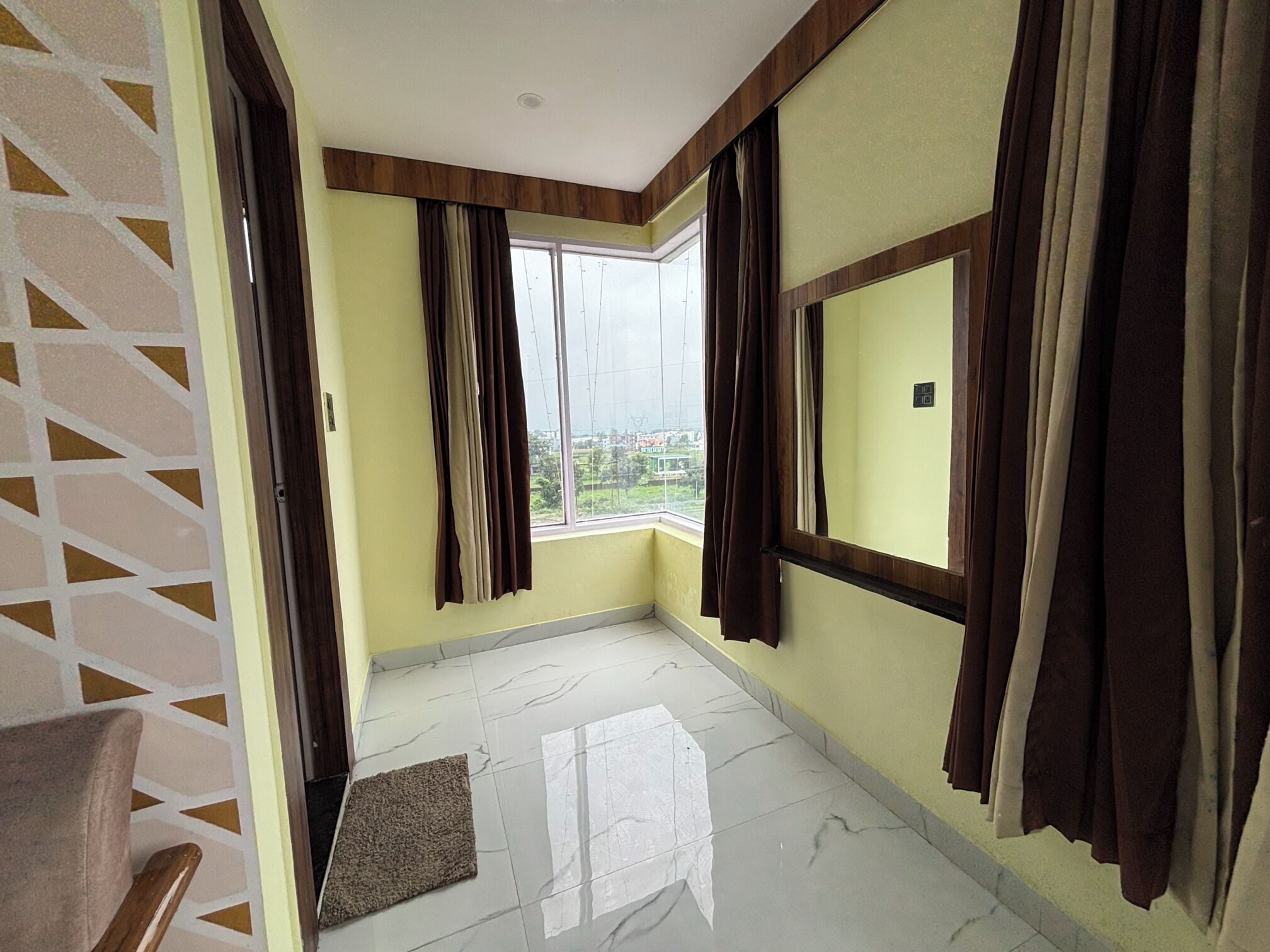 Una habitación con un amplio ventanal, suelo de madera y vista a un paisaje verde.